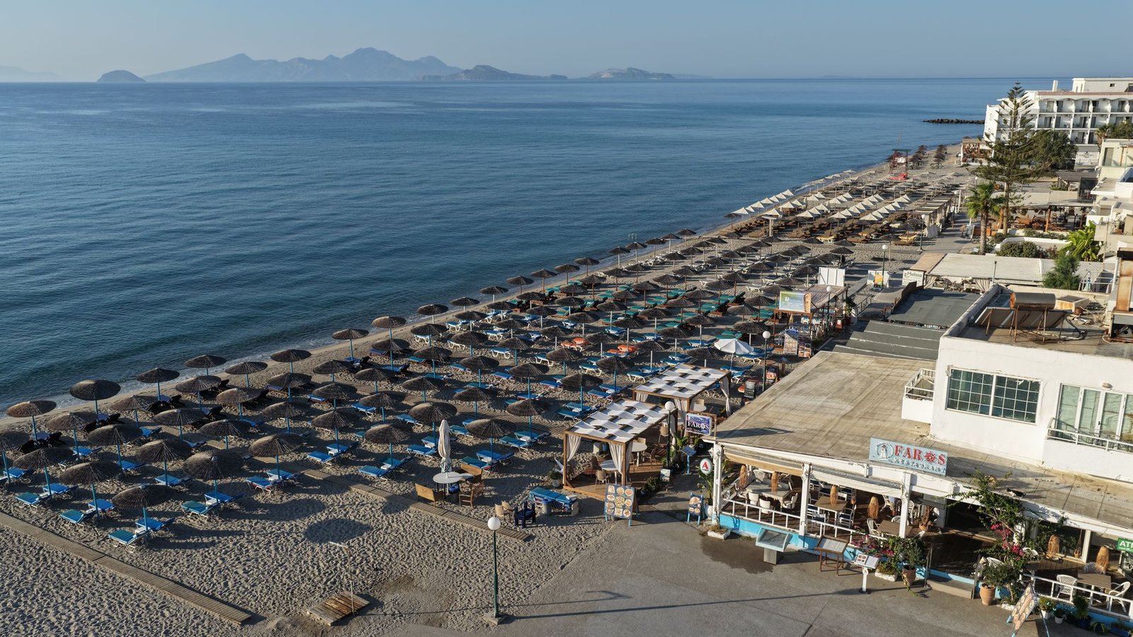 Kardamena beach from the air, with Faros at the near end of the umbrella rows